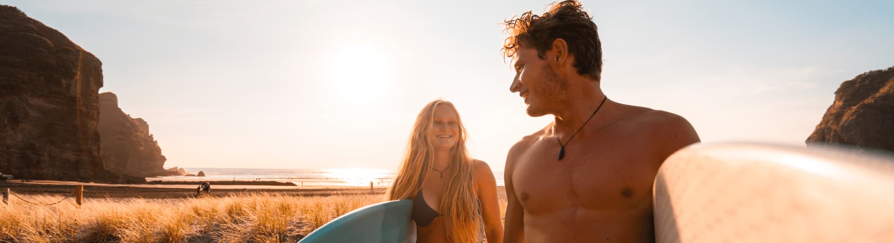 A Man And A Woman Holding Surfboards On A Beach