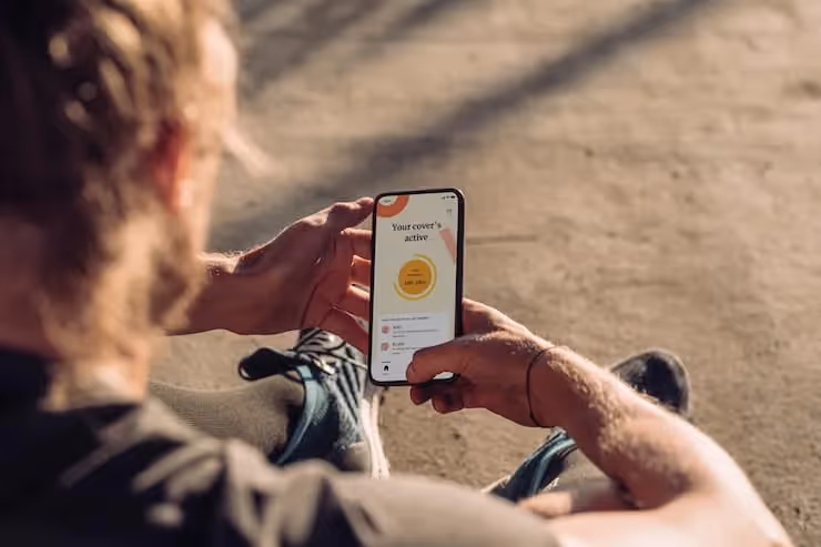 A Person Sitting On The Ground Holding A Cell Phone