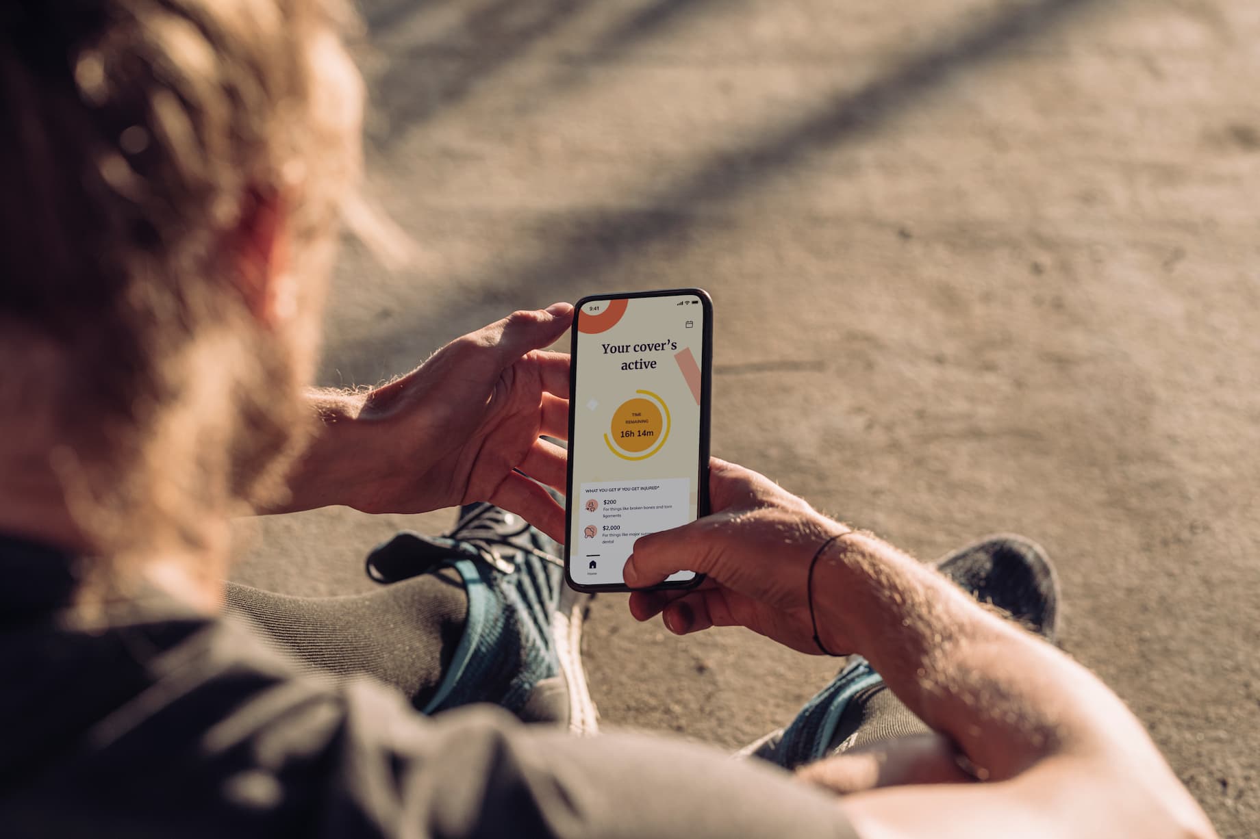 A Person Sitting On The Ground Holding A Cell Phone