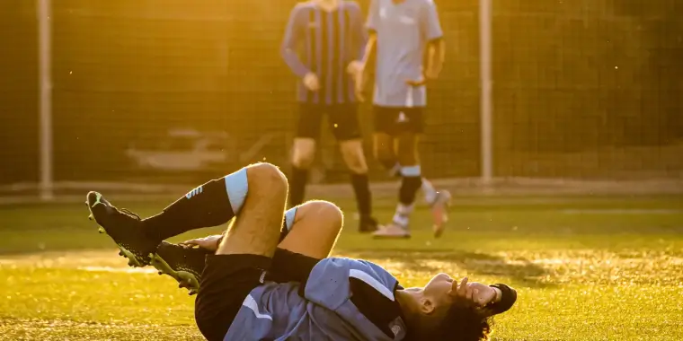 Injured soccer player lying on the field during a match.