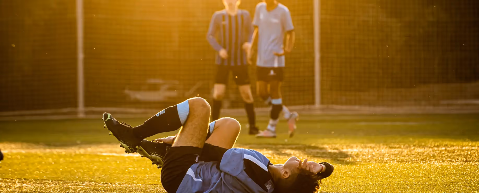 Injured soccer player lying on the field during a match.
