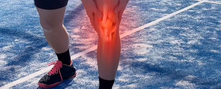Runner holding knee in pain with red overlay indicating injury or inflammation
