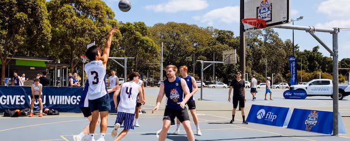 Players competing in an outdoor 3x3 basketball tournament on a sunny day
