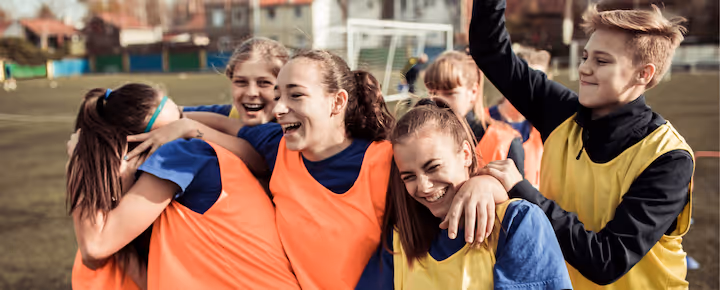 Smiling teen football team celebrating together on the field.