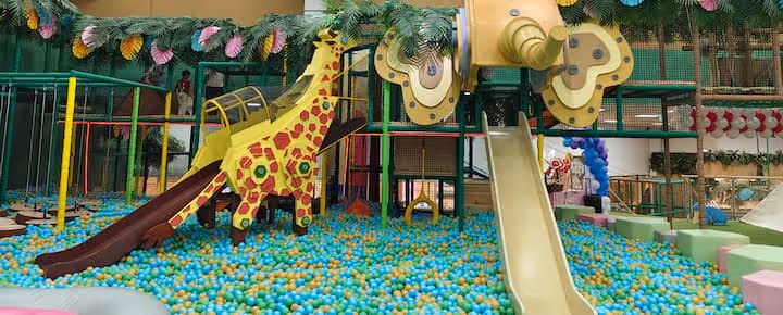 Indoor playground with a giraffe-themed slide, ball pit, and climbing structures.