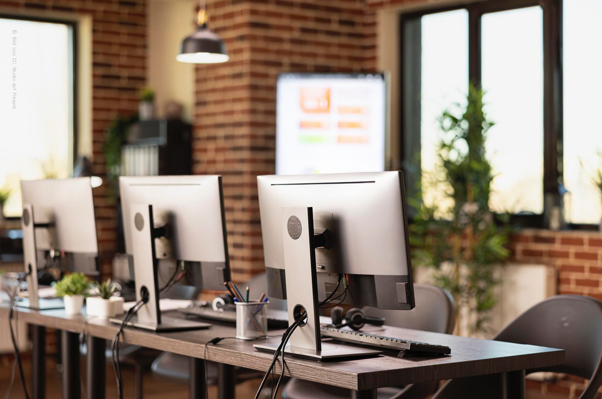 Ein modernes Büro mit Bildschirmen, Tastatur und Headsets.