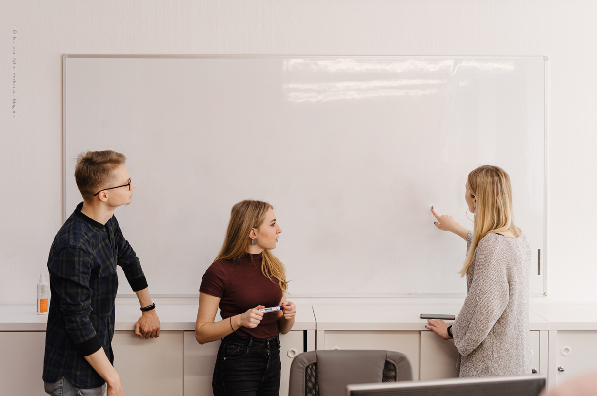 Ein Team von IT-Fachleuten diskutiert angeregt an einem Whiteboard über eine Cloud-Umgebung. Die Atomaspähre ist kollaborativ, während sie Strategien zur Optimierung von IT-Ressourcen und zur Sicherheit in der Cloud erörtern.