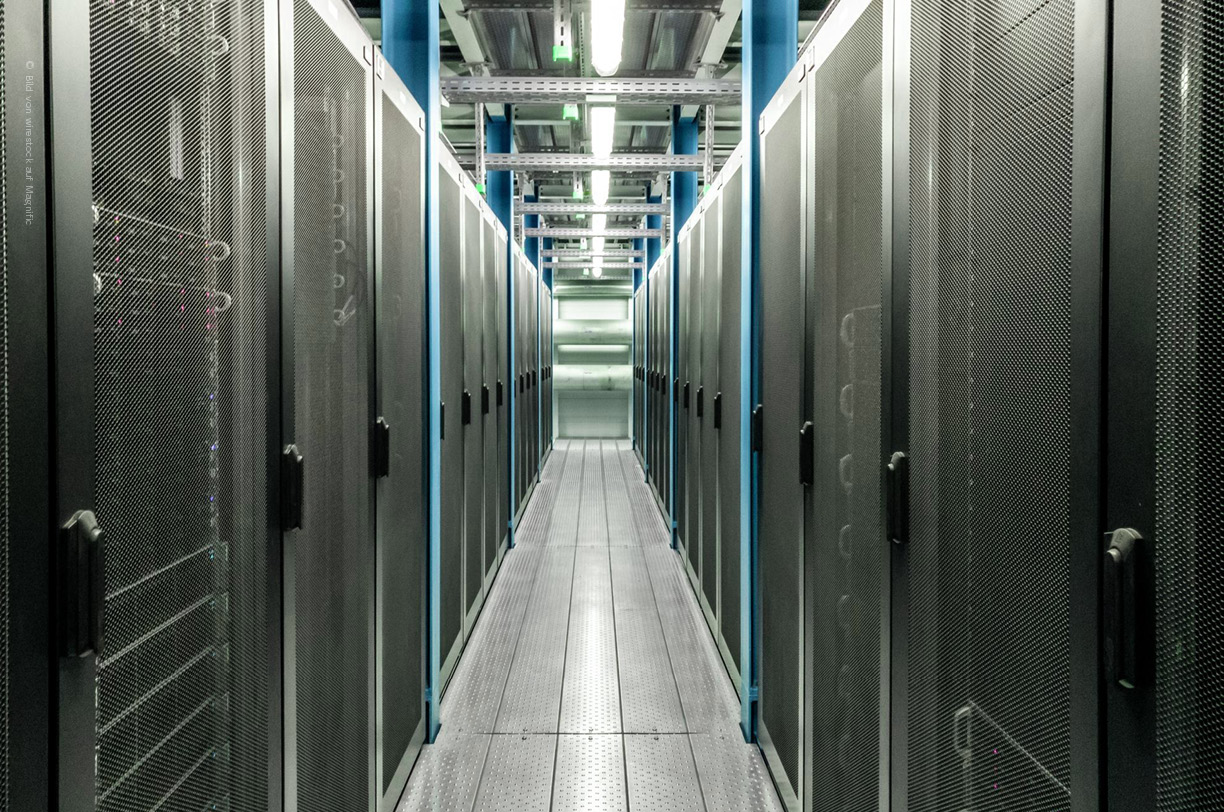 Serverracks in einem gesicherten Rechenzentrum mit Netzwerkkabeln und LED-Anzeigen - die IT-Infrasturktur, die im IT-Sicherheitsaudit auf Risiken geprüft wird. 