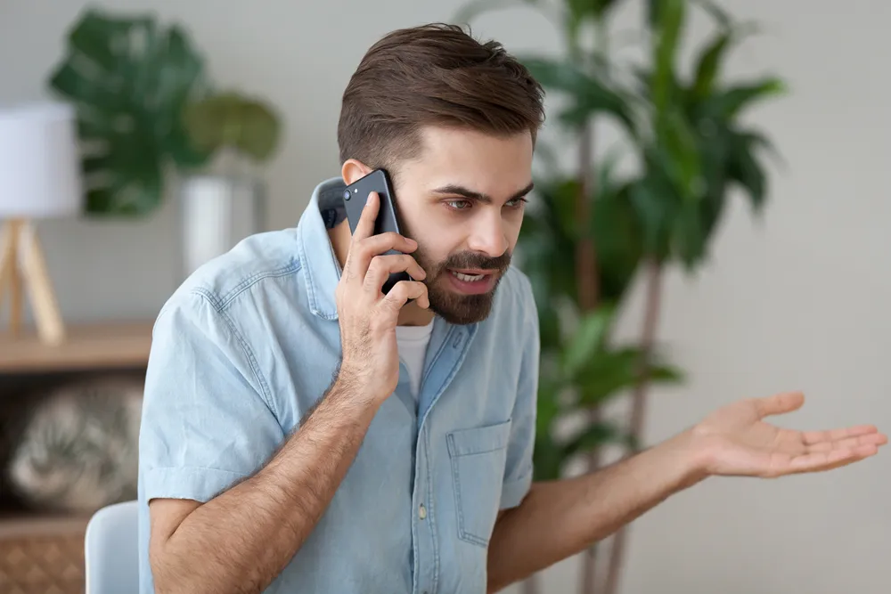 Frustrated customer shouting into a phone — abrasive behaviour that businesses should not reward