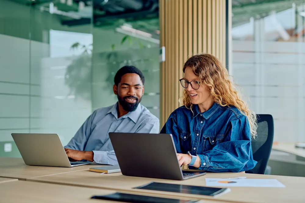 Two-person team working on laptops, the kind of small team monday.com's free plan is built for