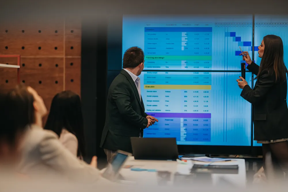 Team reviewing a project schedule on a large screen to plan board structure and workflow