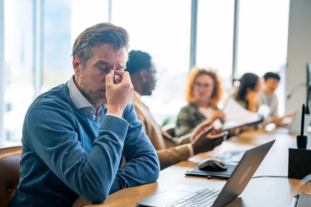 Overwhelmed manager at his desk struggling with a project management setup that has outgrown DIY