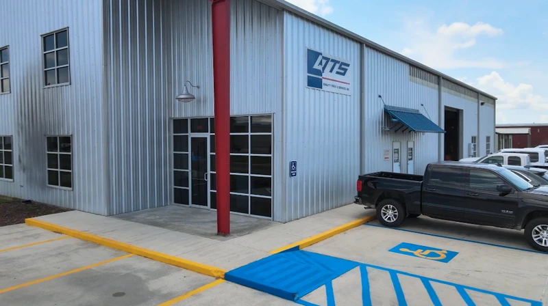 Exterior of the QTS metal industrial building with a black pickup in front and accessible parking spaces.