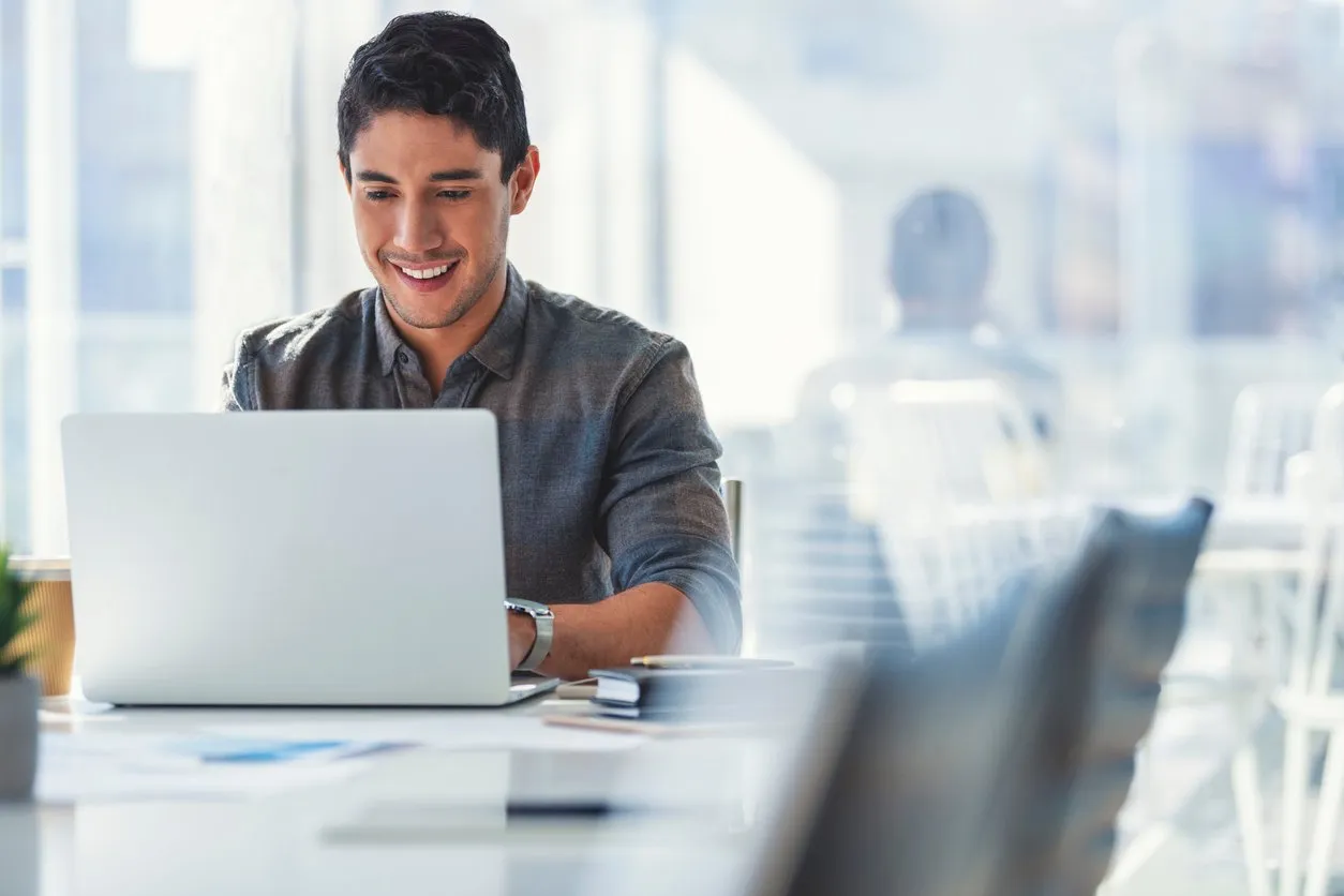 a man uses a laptop computer at a desk in a modern office
