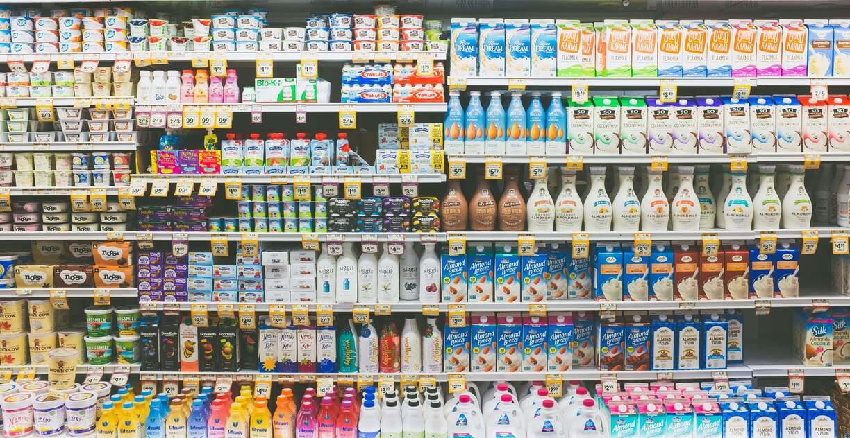 discount grocery store dairy aisle, showing a colorful assortment of milk, cream, yogurt, and other refrigerated products