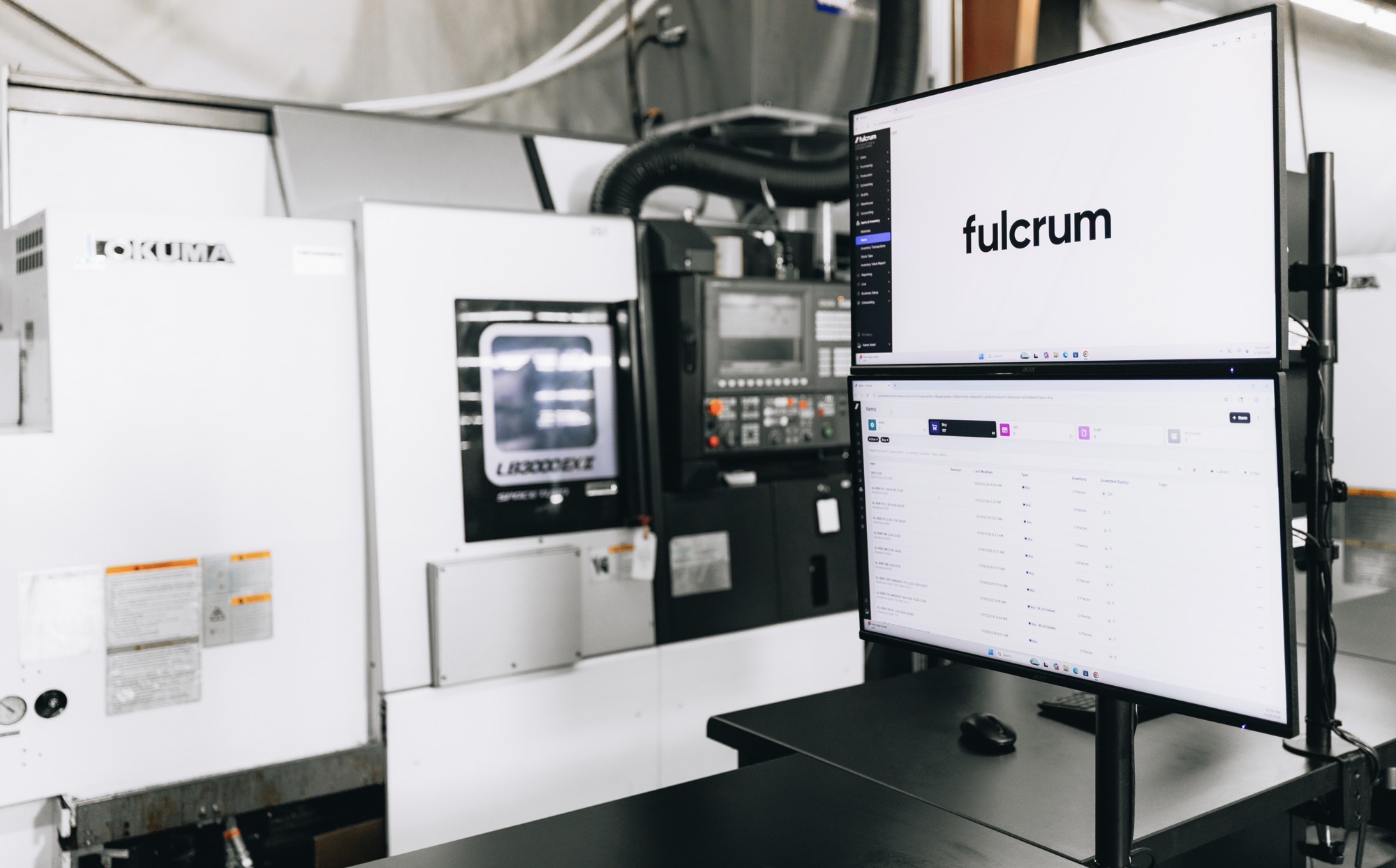 Fulcrum open on a dual-monitor station beside an Okuma turning center at Northeast Tool