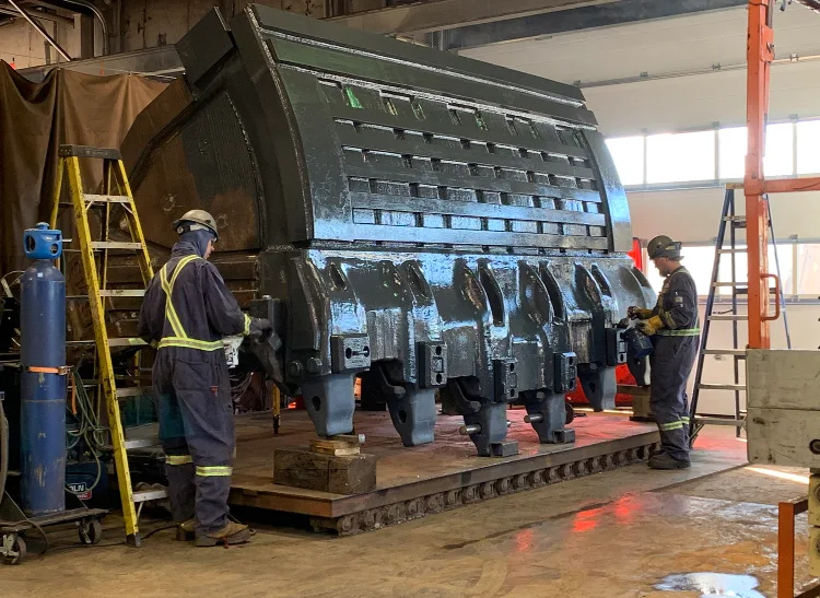 Two JADCO fabricators fitting wear plate to a large mining bucket