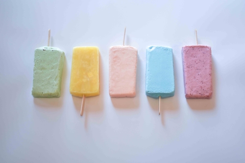 A neat row of popsicles in a variety of colors