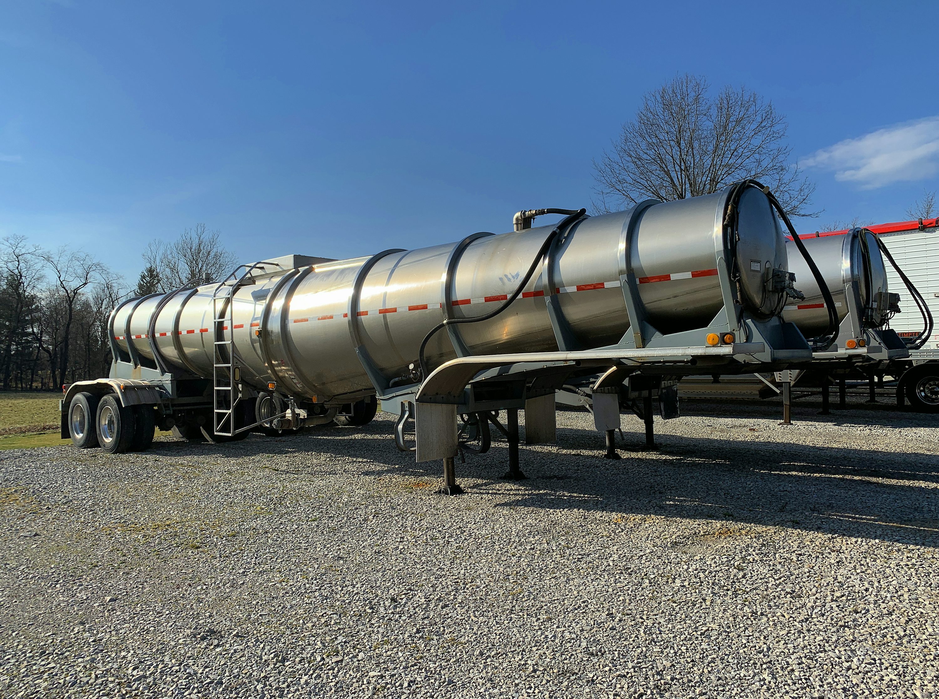 a large silver tanker truck parked in a gravel lot