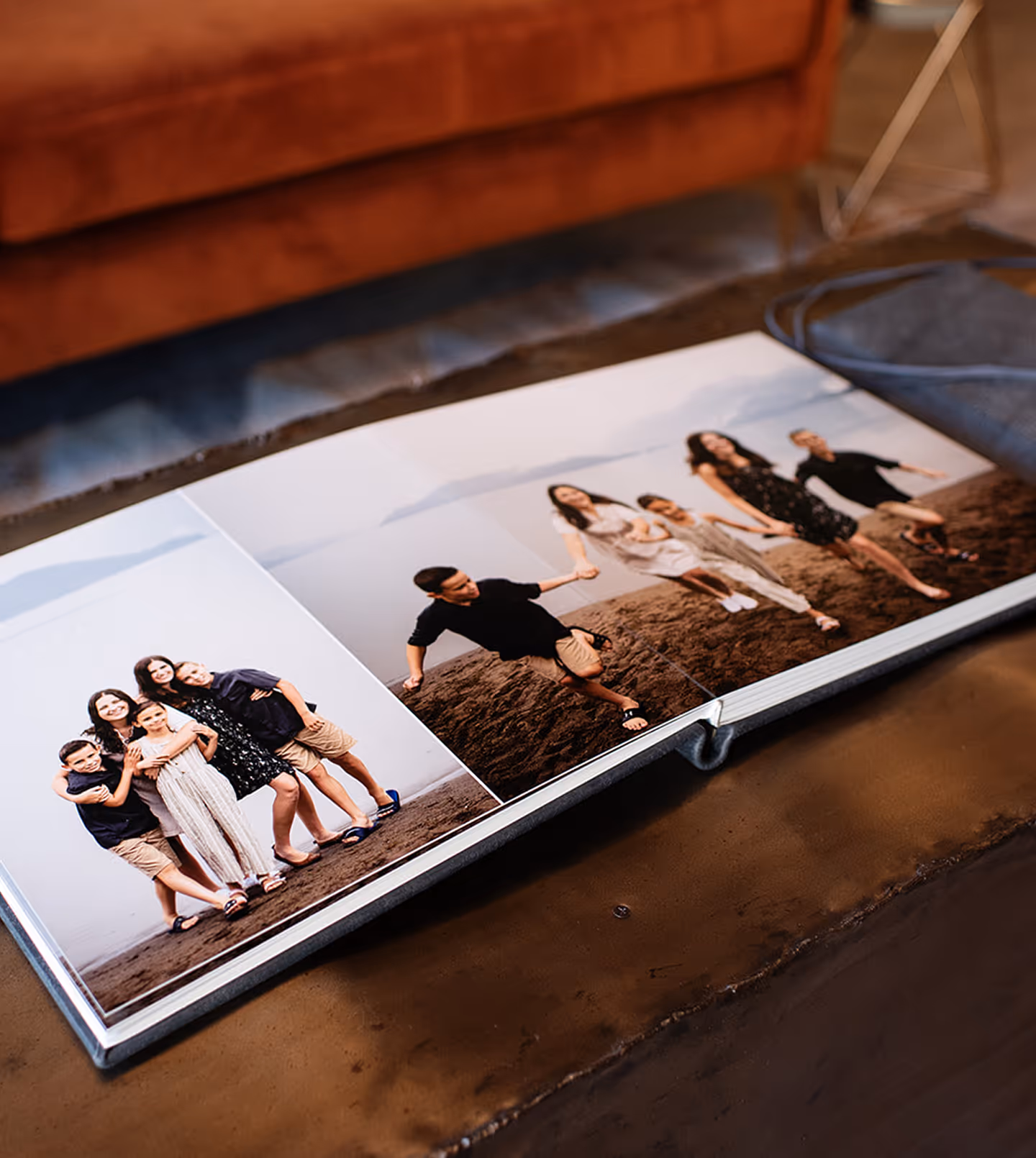 Open photo book on table showing two photos of a family with children at the beach.