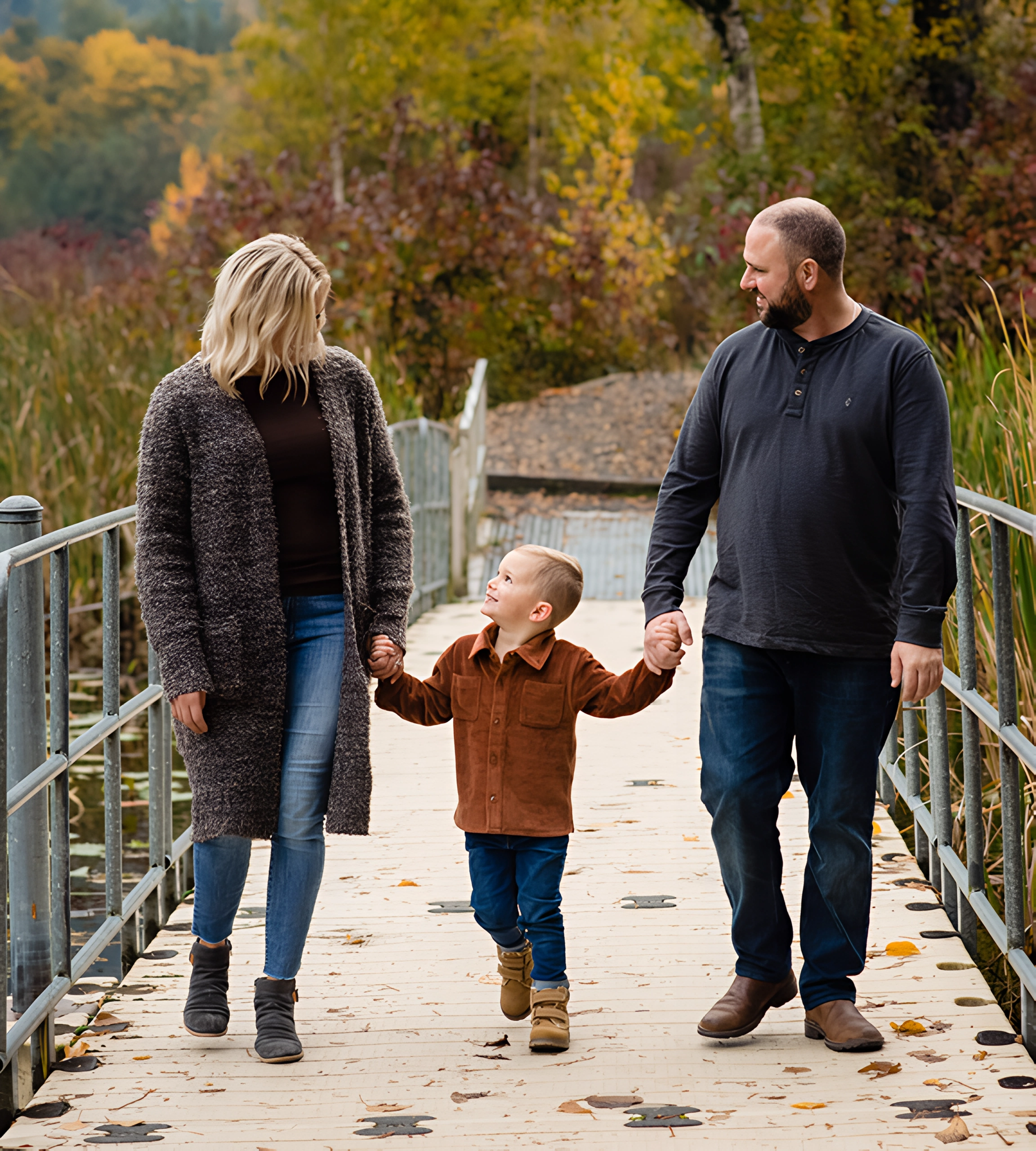 A man and woman holding hands while walking with a small boy.