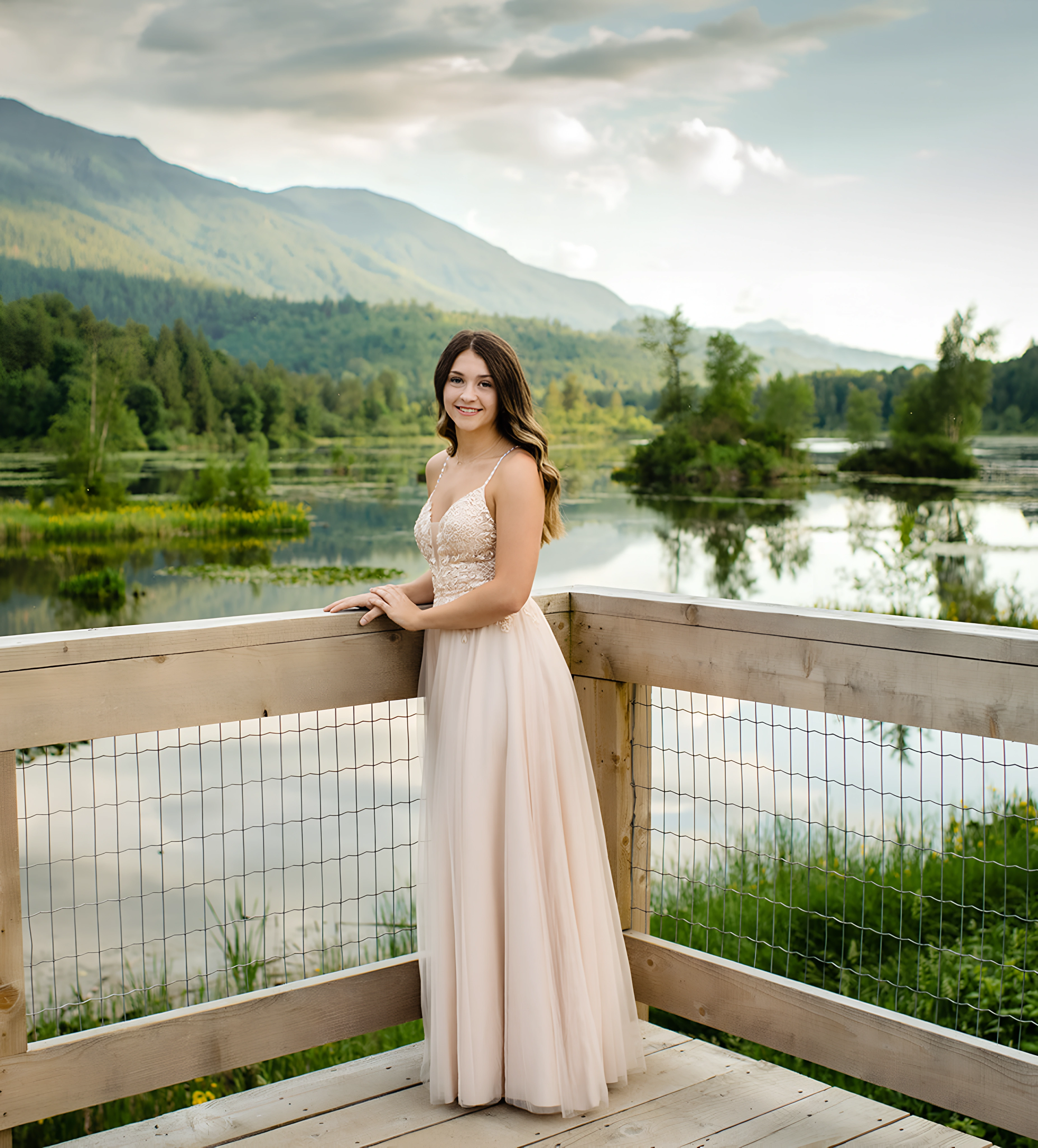A woman standing on a wooden deck next to a lake.