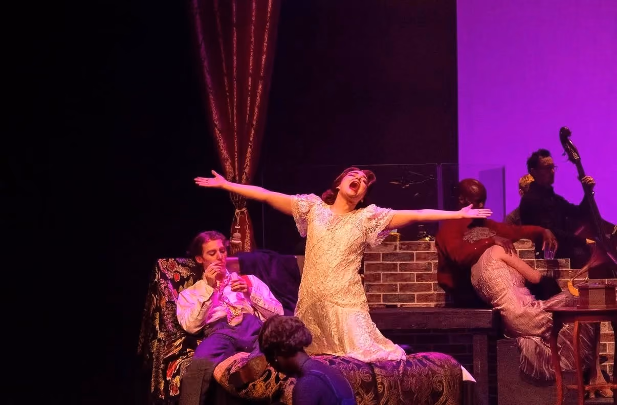 Ally as Nadine in The Wild Party, on stage, arms wide and mouth open mid-song.