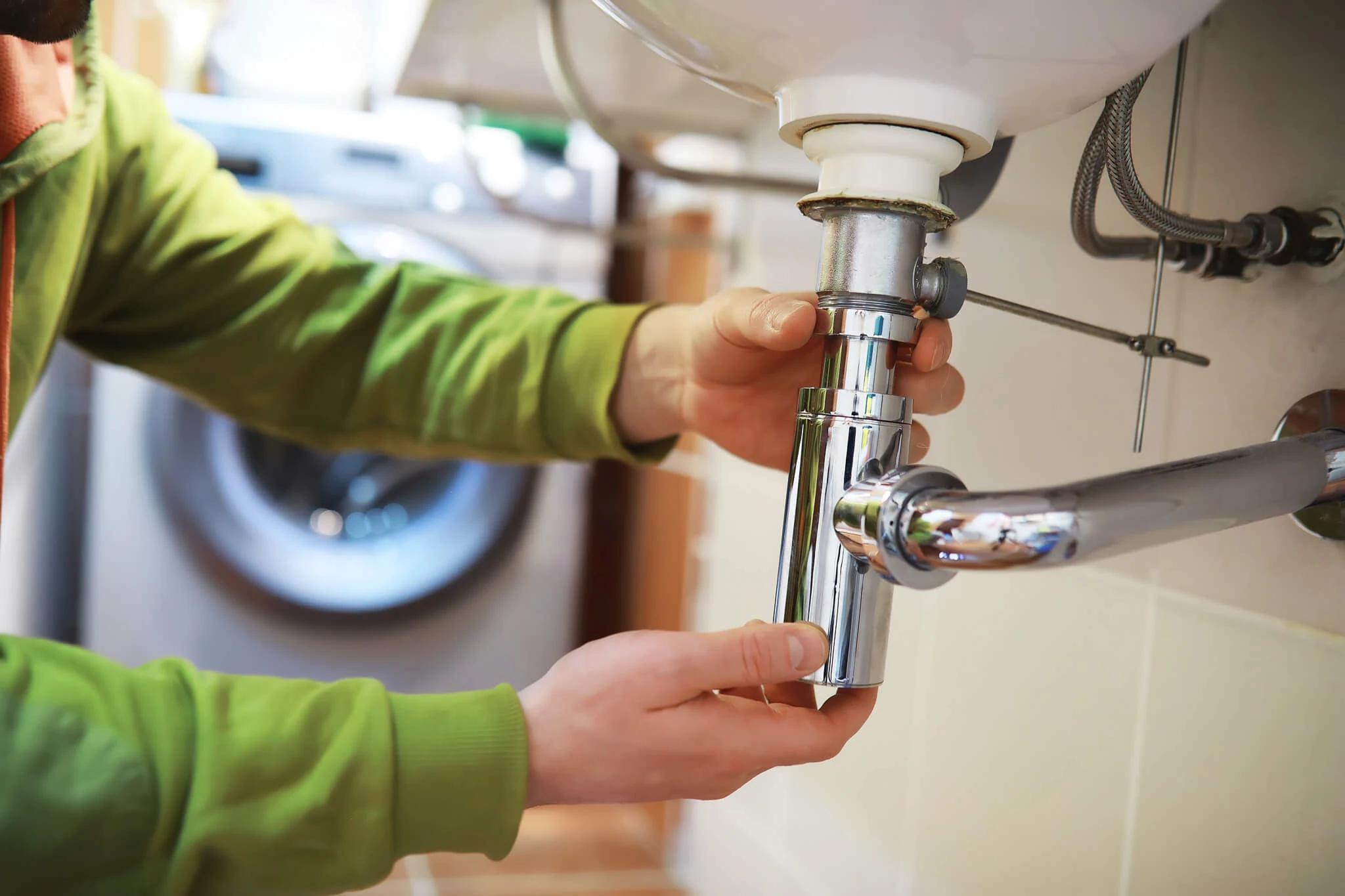 Plumber inspecting a pipe connection under a kitchen sink