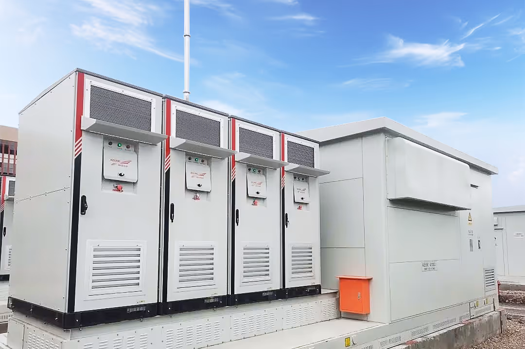 Row of large white industrial electrical cabinets mounted on a concrete platform under a blue sky with scattered clouds.