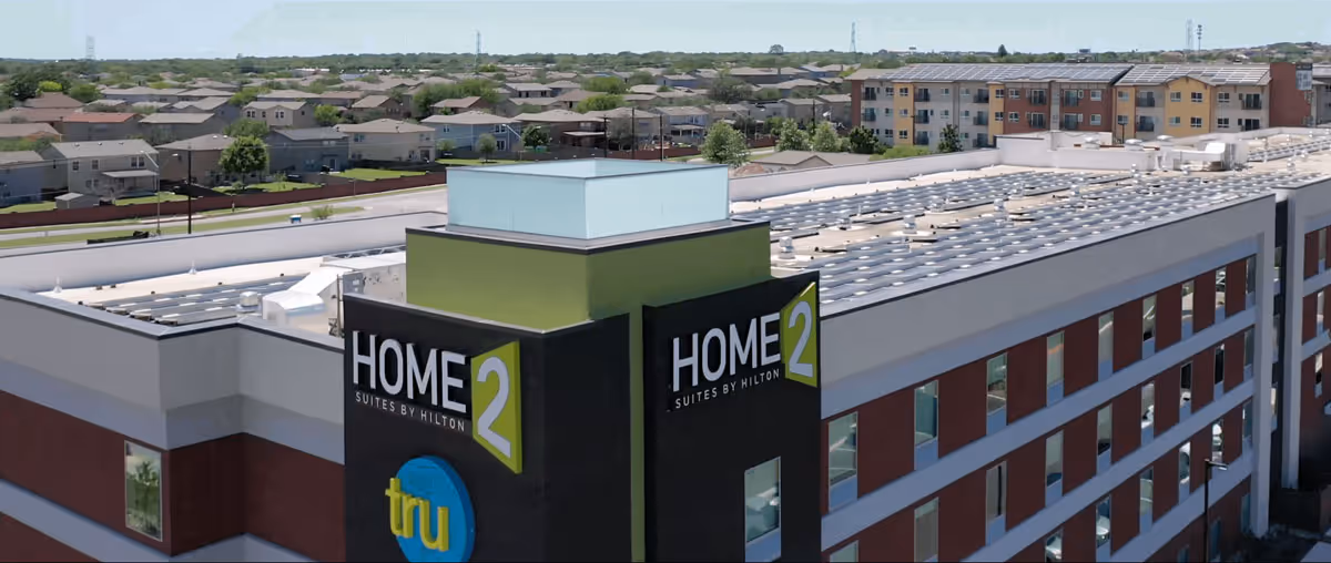 Aerial view of a Home2 Suites by Hilton hotel building with solar panels installed on the roof.