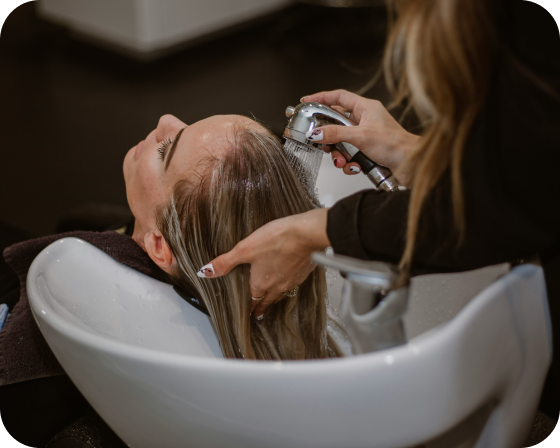 Profesional lavando el cabello a una clienta en una peluquería