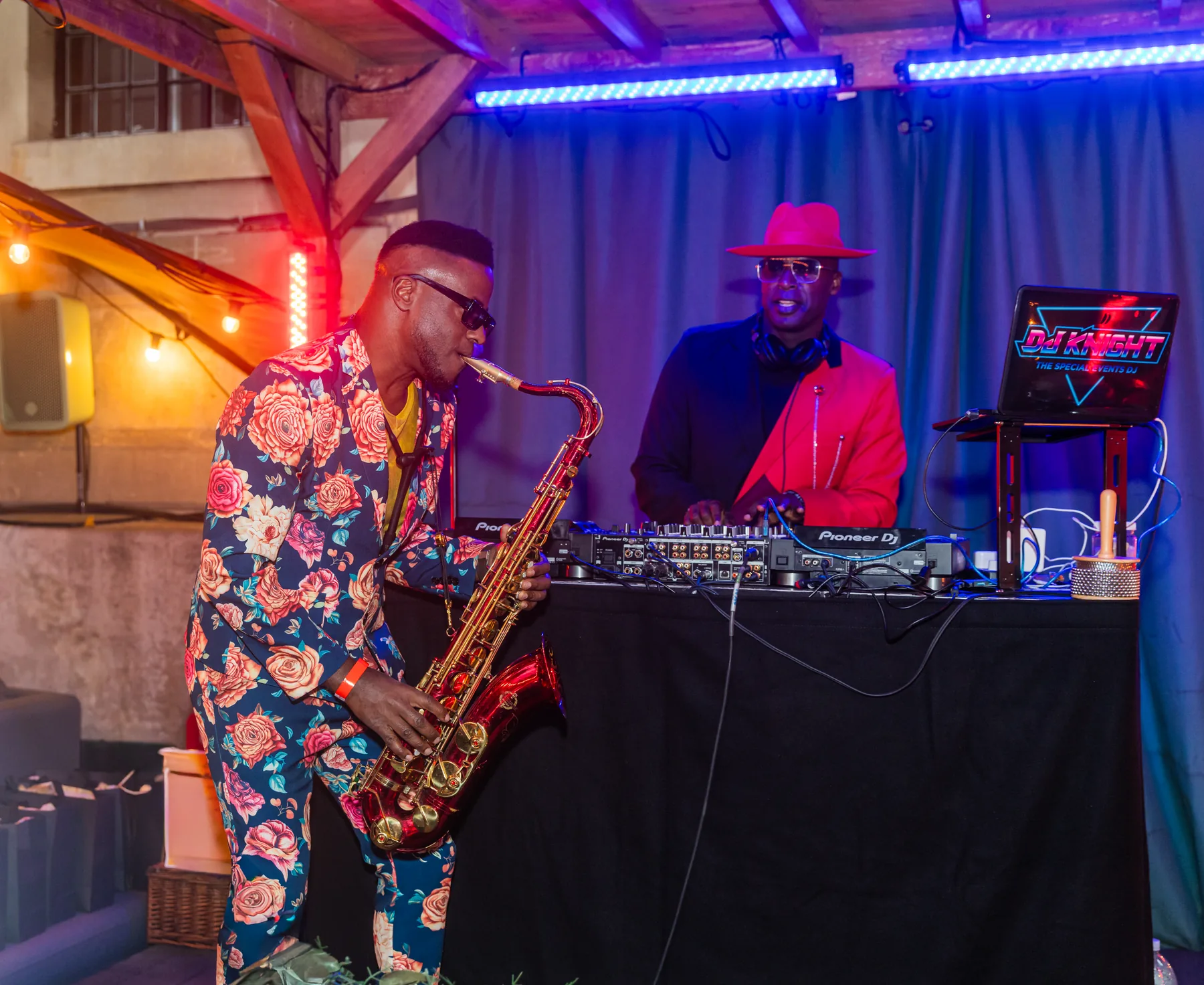 Saxophonist performing beside a DJ booth at an indoor event