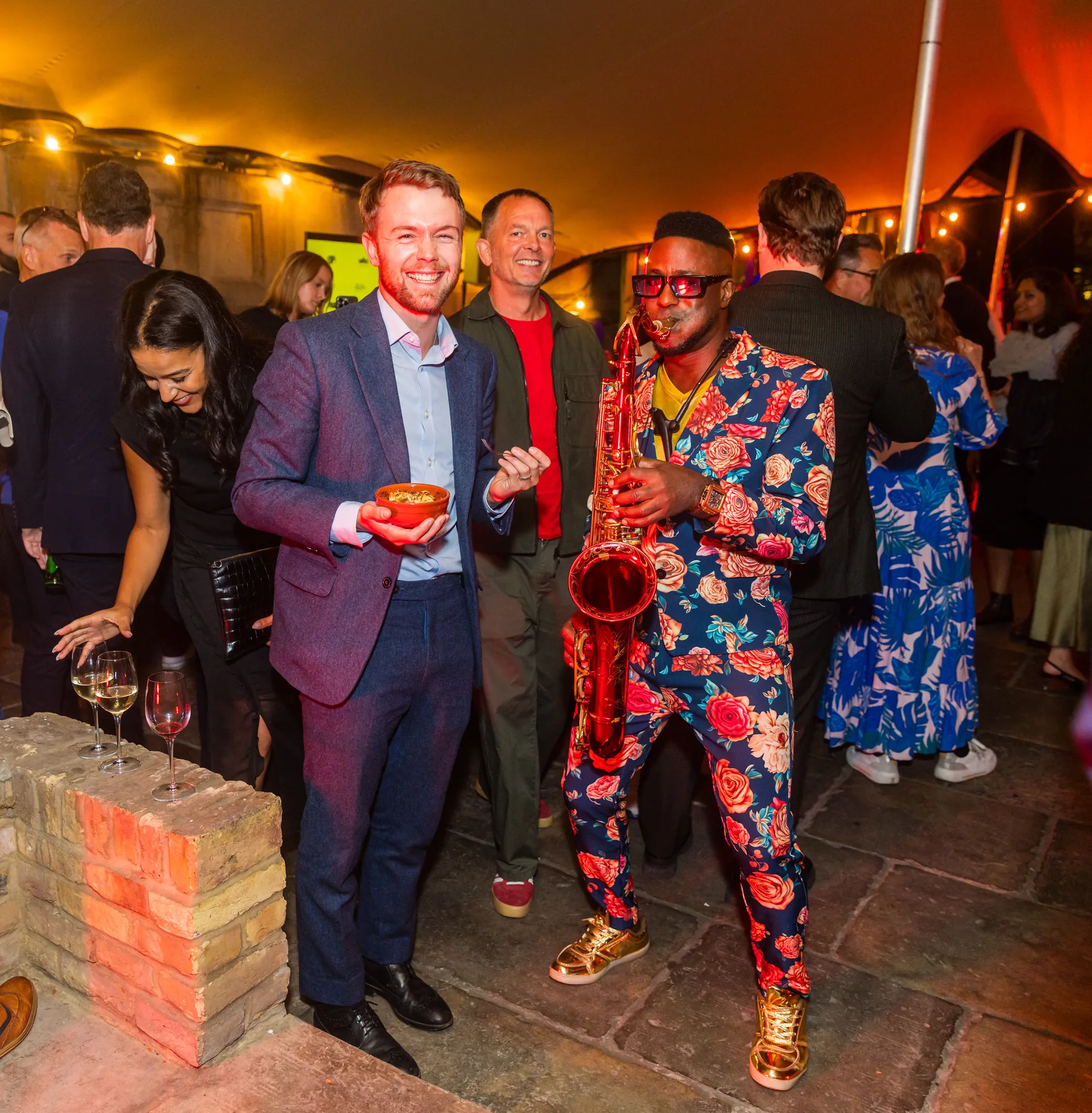 Saxophonist engaging with standing event guests