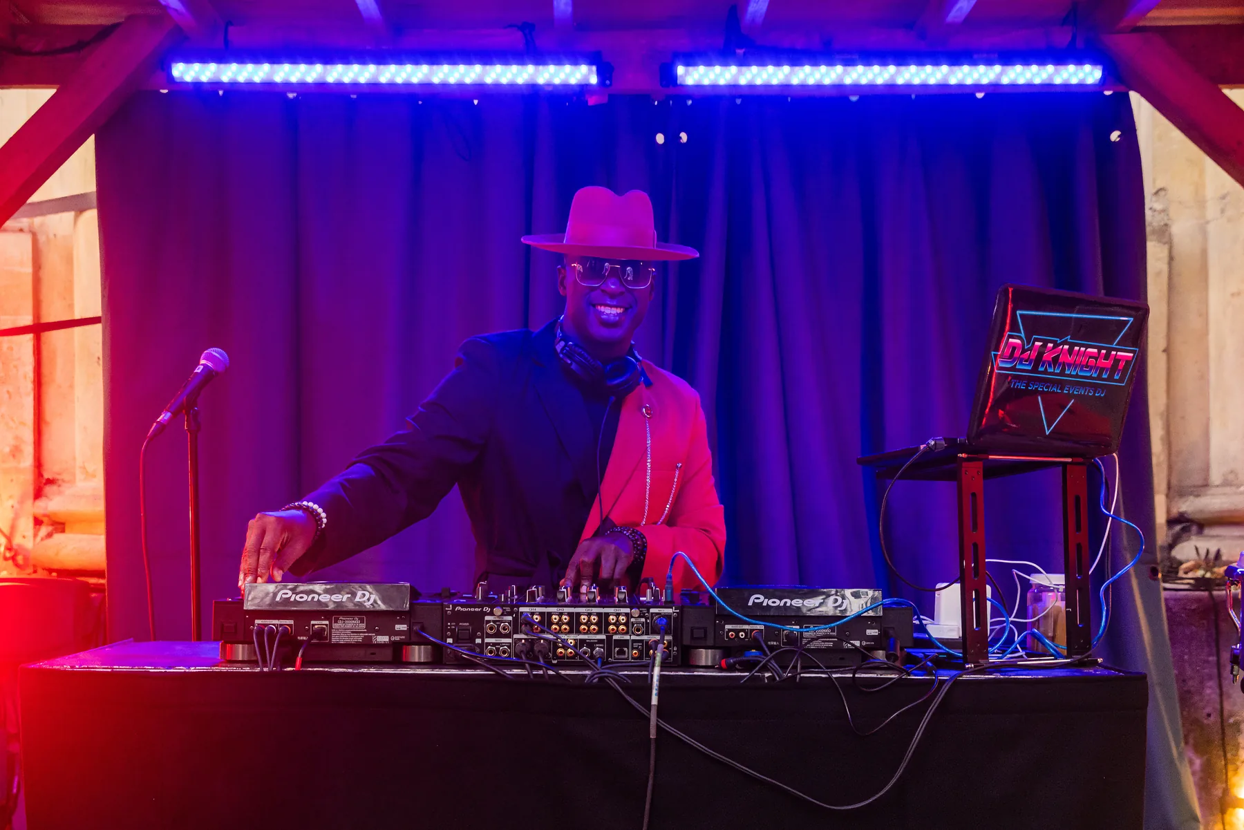 DJ mixing music under blue and magenta event lighting