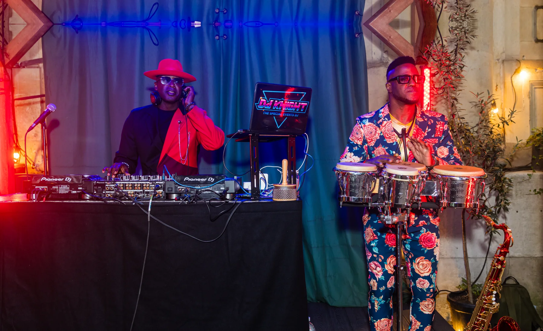DJ and live musician performing at a company event, with a saxophone beside them