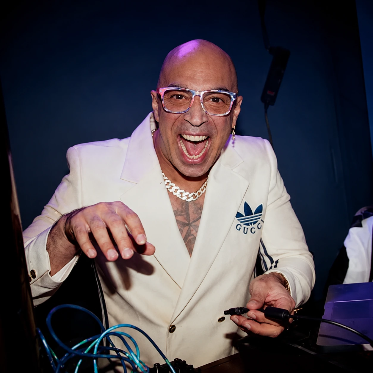 DJ Hatim Funky in a white jacket performing at a DJ booth