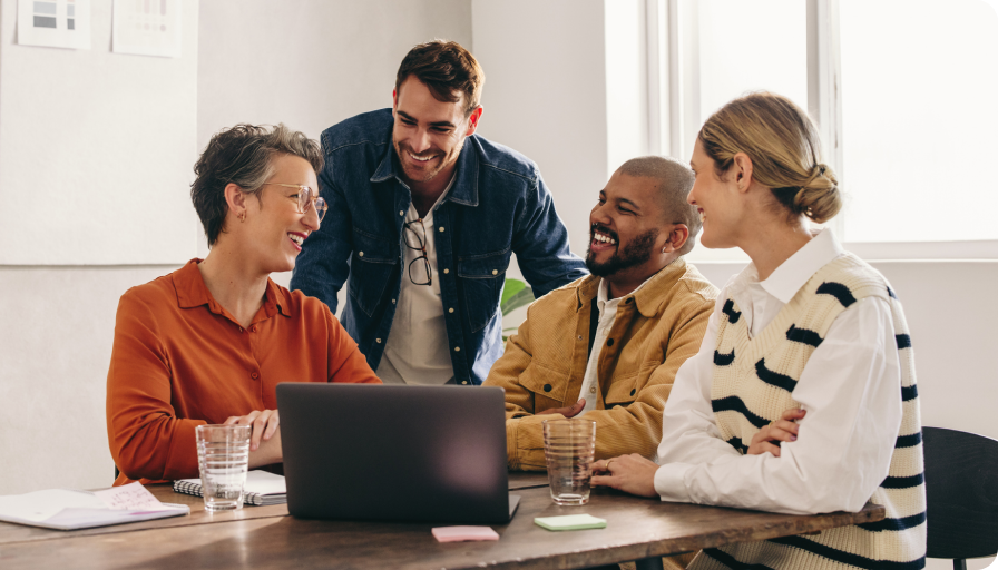 A collaborative team gathered around a laptop