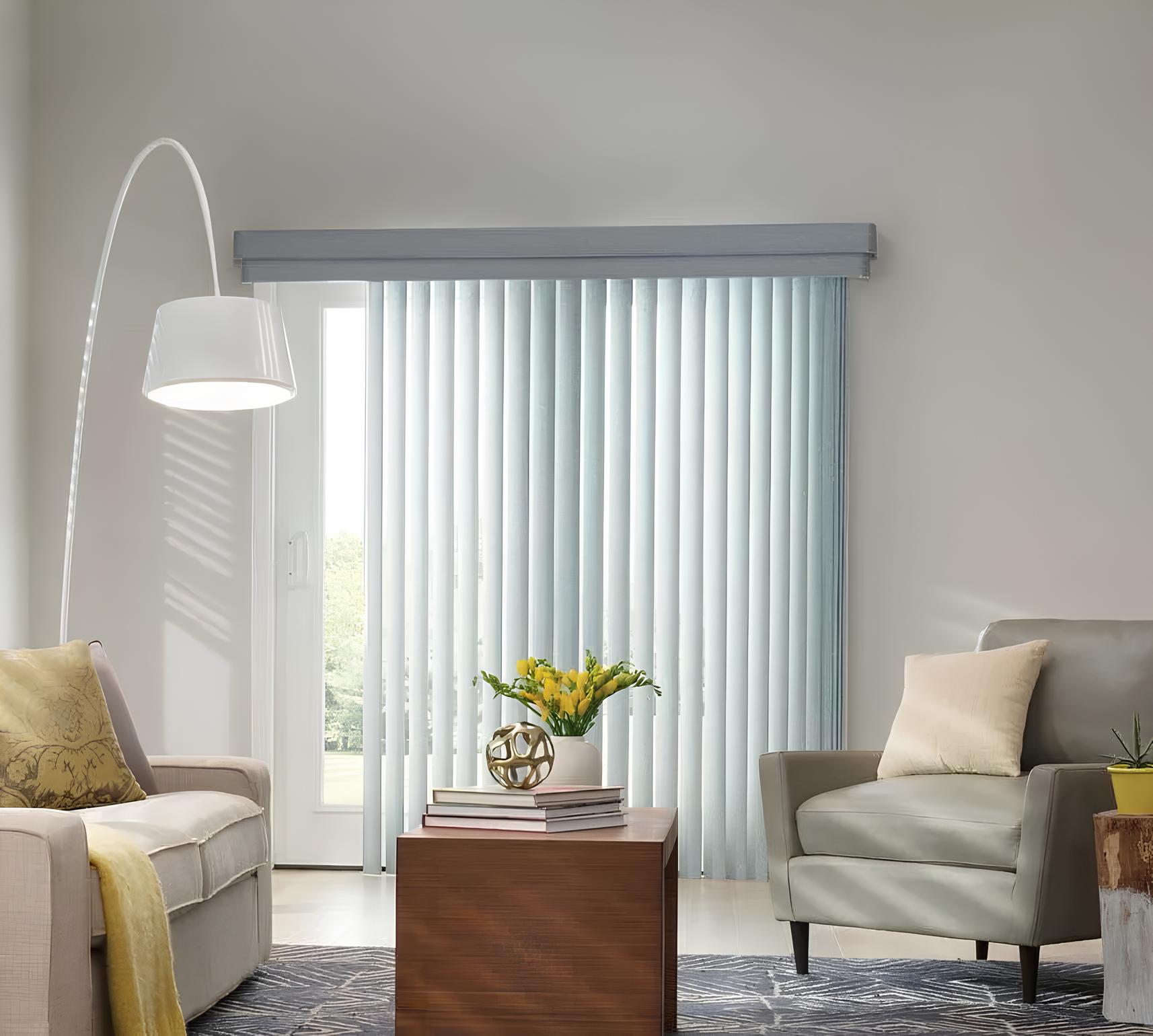 Vertical blinds in living room with lamp, couch, chair.