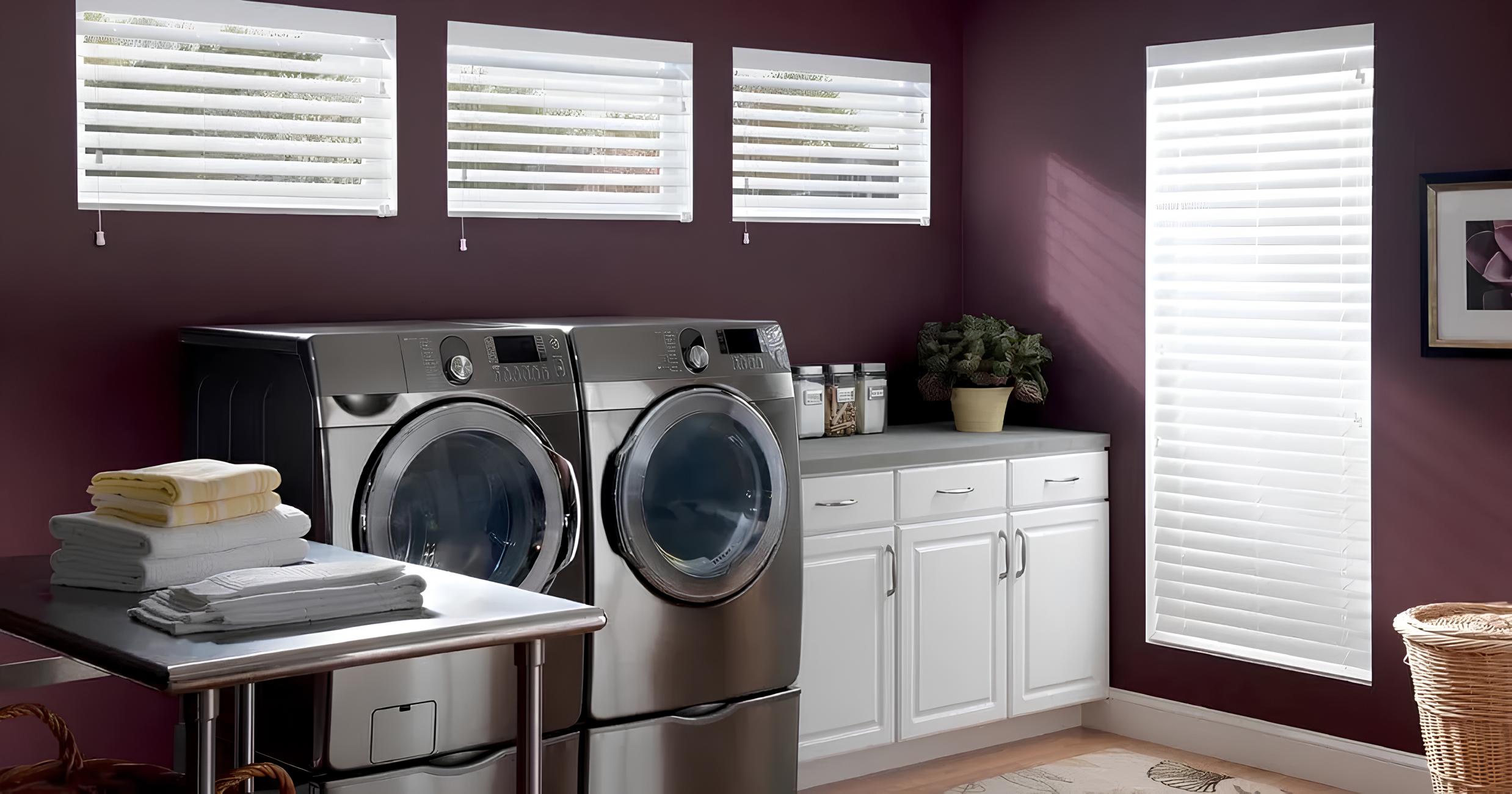 Laundry room with steel appliances, white blinds, and cabinets.