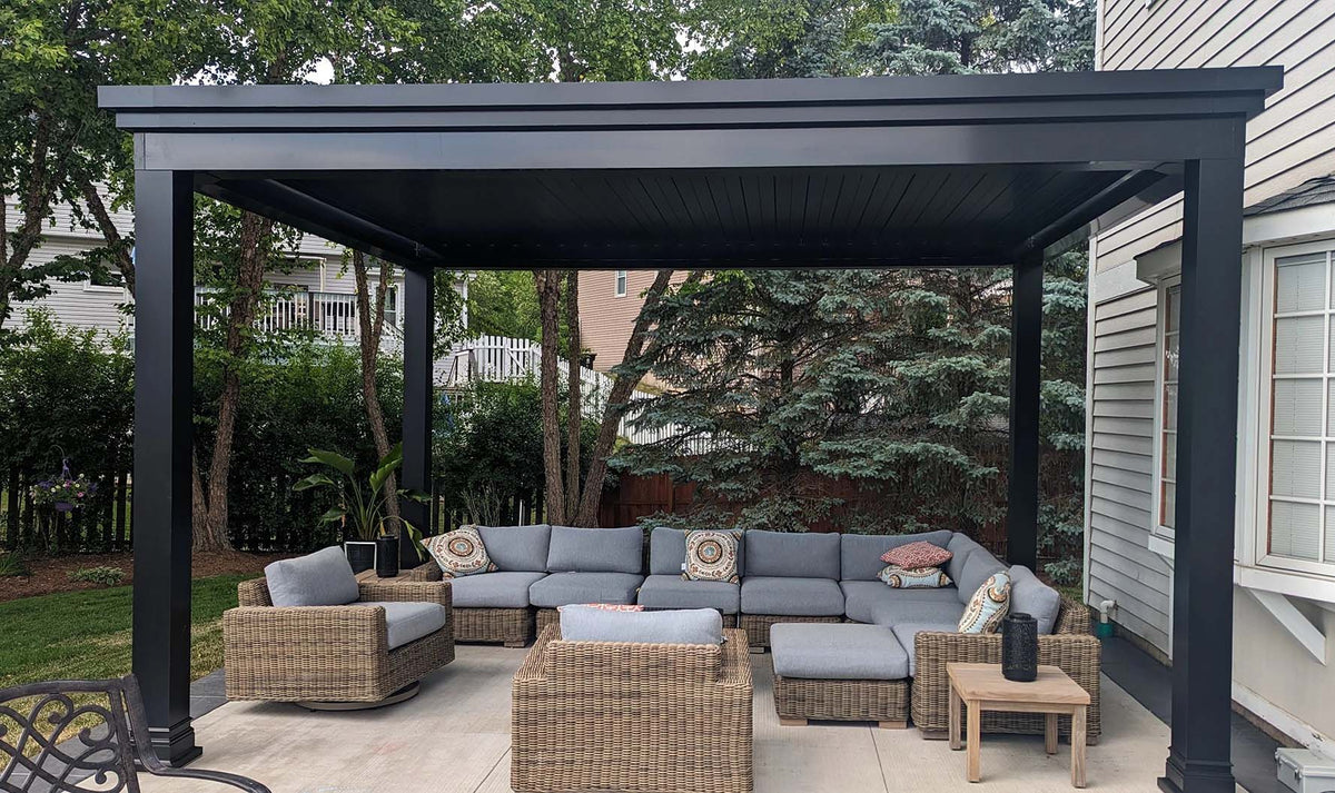 Outdoor patio with modern black pergola, gray cushioned wicker sectional sofa, and small wooden side table.