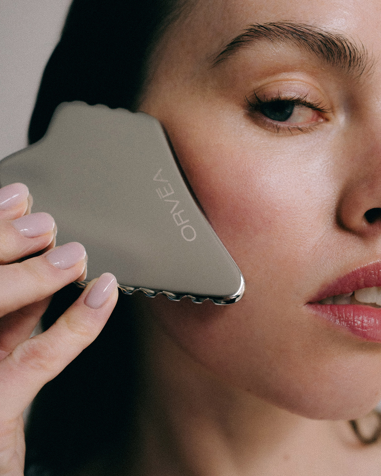 Beauty-Anwendung mit einem ORVEA Gua-Sha-Tool im Gesicht einer Frau.