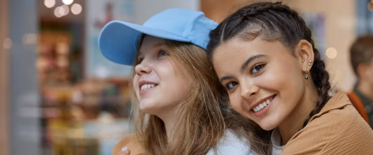 Two young teenage girls smiling and hugging in a shopping centre. Life insurance for people with diabetes.