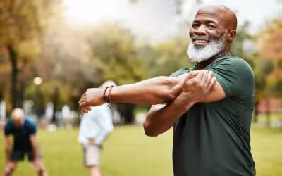 older man outside doing arm stretches whilst exercising