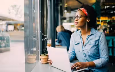 Lady with headphones in with laptop sitting in window of cafe. What is NHS Right To Choose? Find Out What Your Choices Are