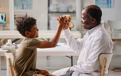 Boy giving high-five to his GP after his appointment. Private GP vs NHS GP.