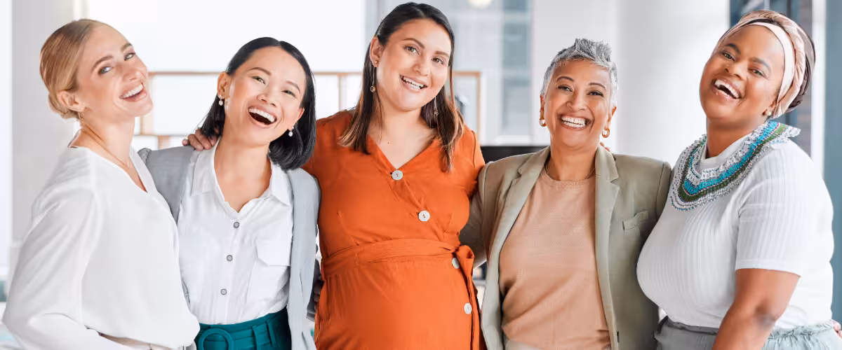 Group of women of all ages, standing together, smiling. Guide to Women’s Health Checks: NHS & Private Options