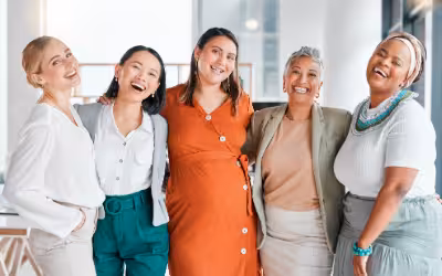 Group of women of all ages, standing together, smiling. Guide to Women’s Health Checks: NHS & Private Options