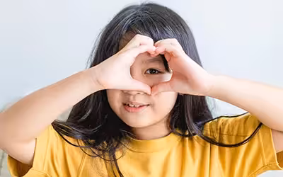 Healthy eyes and vision. Portrait happy child holding heart shaped hands on eyes.