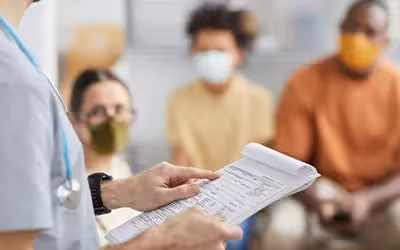 Close up of male doctor holding clipboard while talking to patients waiting for their appoinments. Your Options If You're Stuck On An NHS Waiting List
