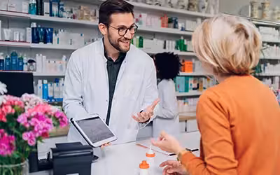 Portrait of a male pharmacist working at the counter in pharmacy. Antibiotics in the UK: Access and Prescription Guidelines